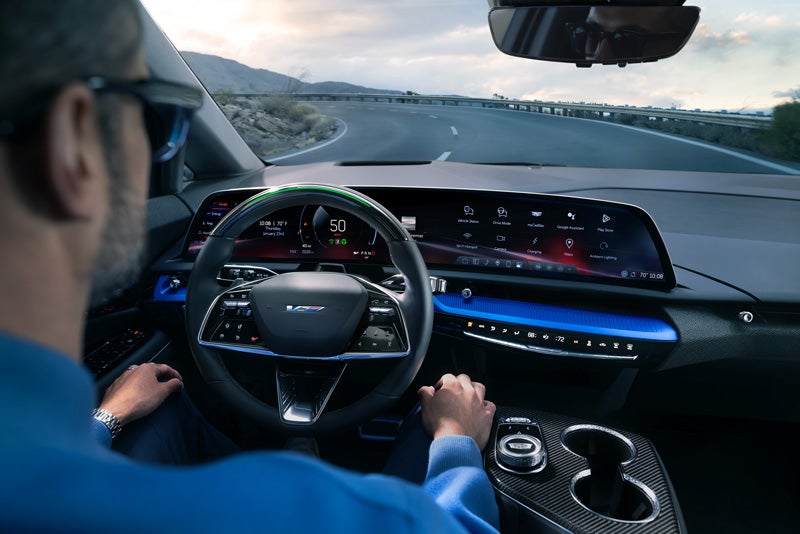 Front View of the 2026 OPTIQ-V Driving Through the Dusk Utilizing its Headlights | Capital Cadillac Of Atlanta in Smyrna GA