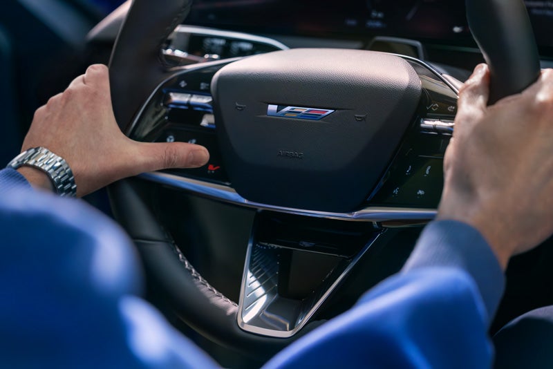 Close-up of a Man About to Press the V-Button on the 2026 OPTIQ-V Steering Wheel | Capital Cadillac Of Atlanta in Smyrna GA