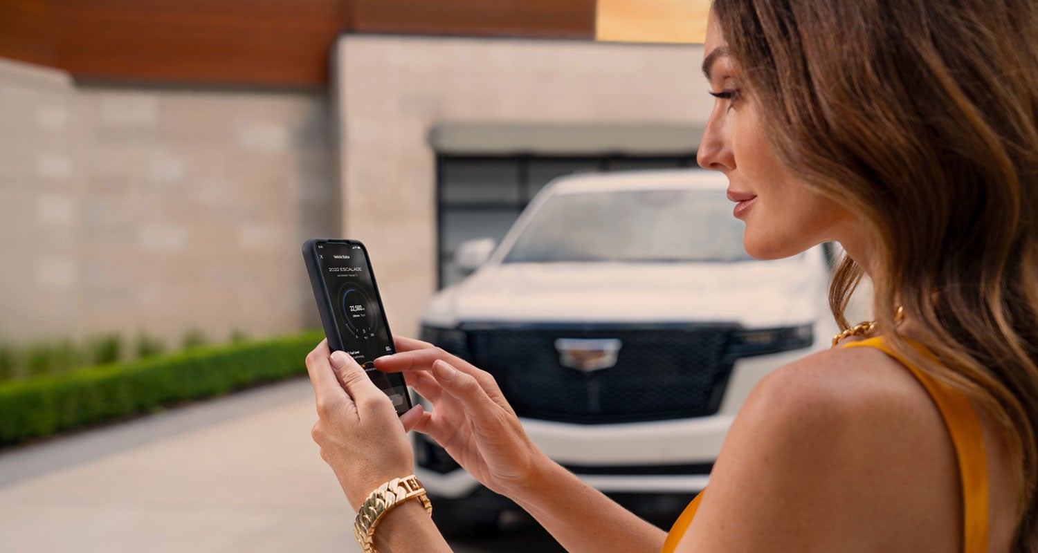 lady checking her mobile with a Cadillac vehicle background | Capital Cadillac Of Atlanta in Smyrna GA